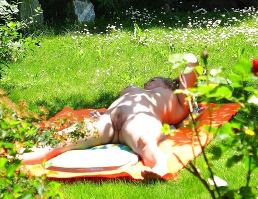 Esposa desnuda tomando el sol acosada en el jardín