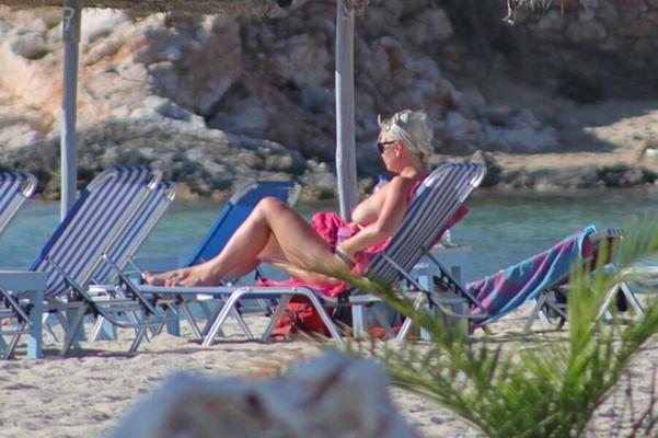 Nena rubia se pone la parte superior del bikini en New Golden Beach, Paros