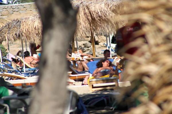 Chica con pelo rizado atrapada en topless en la playa de Paraga, Mykonos