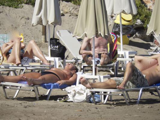 Garota com peitos grandes e bronzeados pega em topless em Agia Marina, Creta